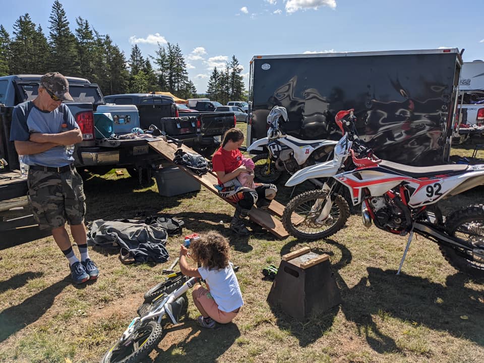 Family relaxing surrounded by dirt bikes and equipment