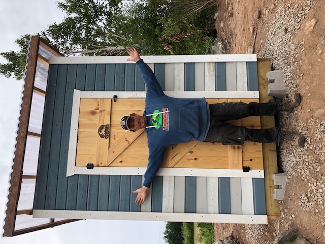 Josh in front of the new outhouse
