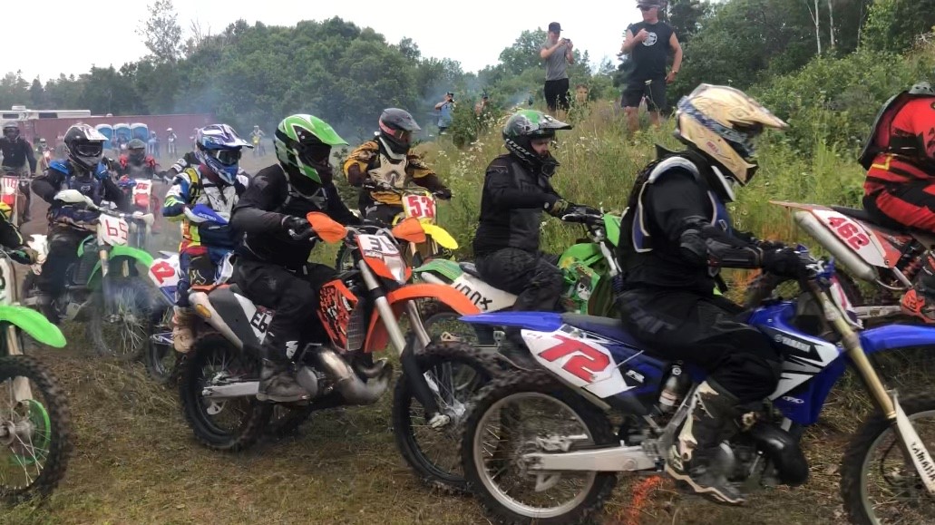 Many riders racing to the holeshot line at the start of a scramble