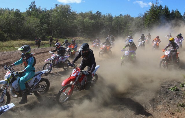 Dirt bike racers take off from the start of Miller Meadow with dirt flying