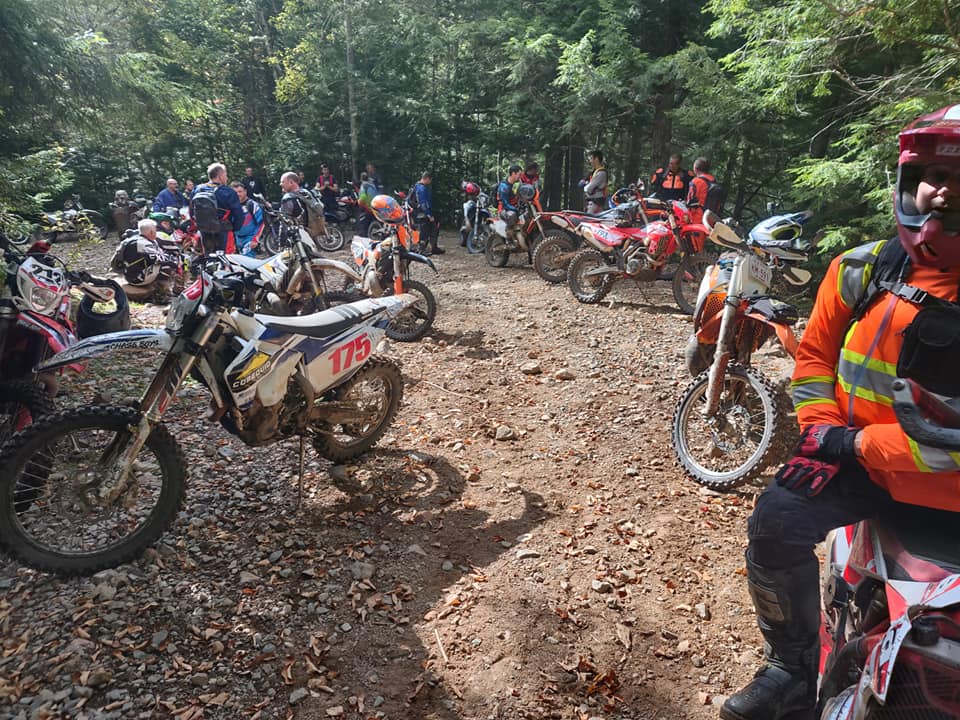 dirt bikers on a break standing around in a clearing