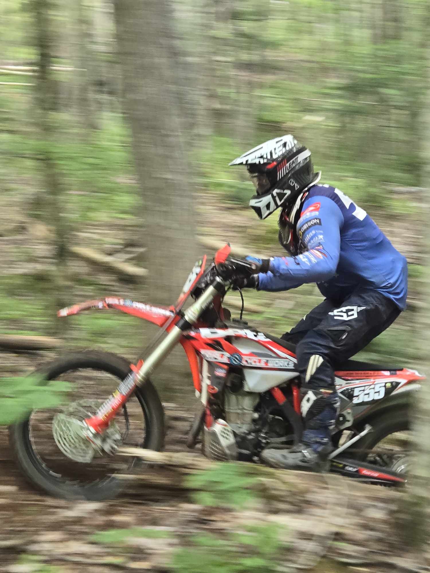 Rider racing through the woods on their dirt bike