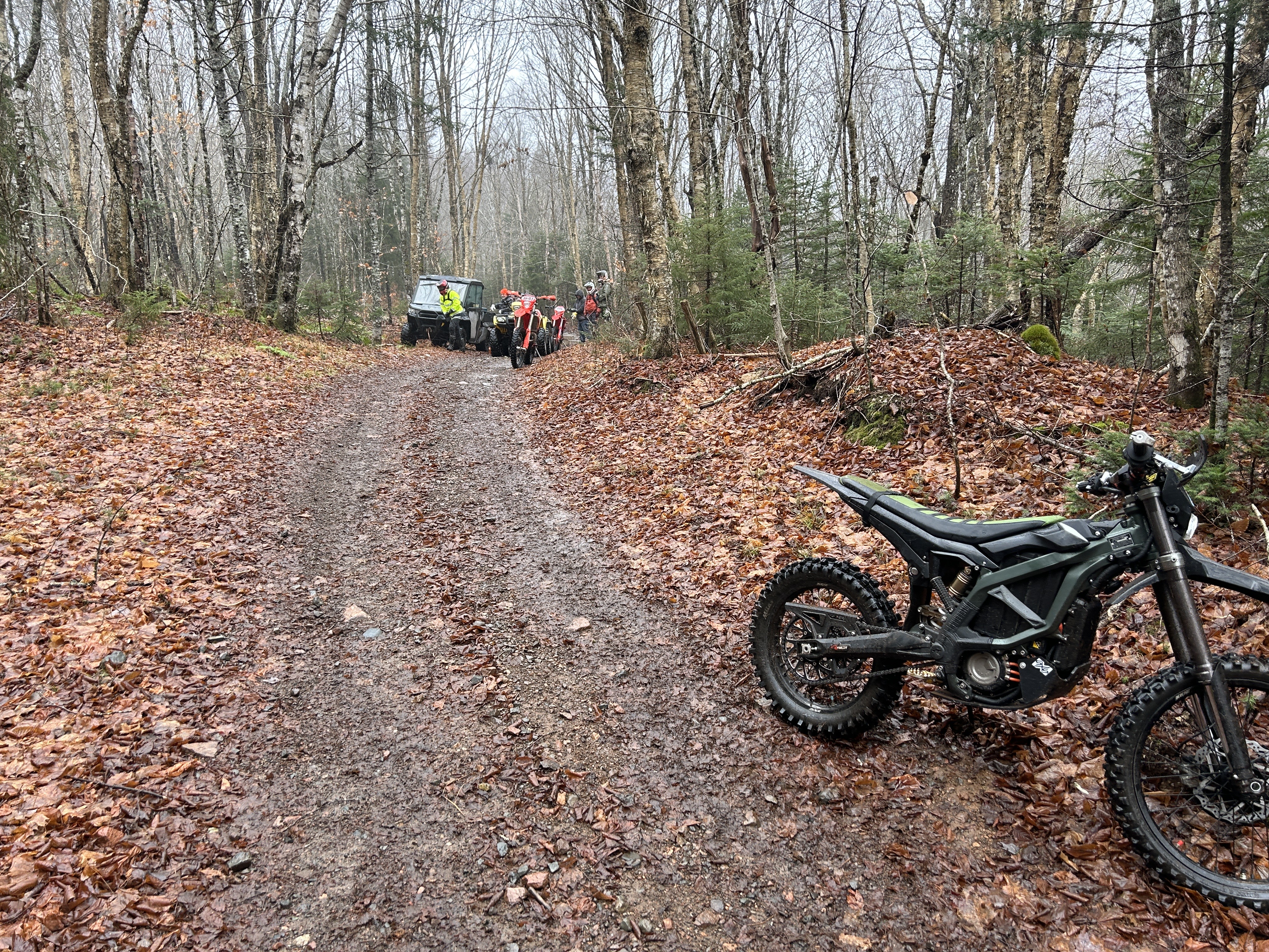 dirt bike in the foreground and work team to clear trail in the background