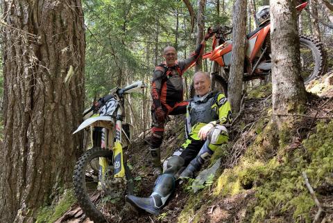 Neil and Nick with their dirt bikes on a wood hill