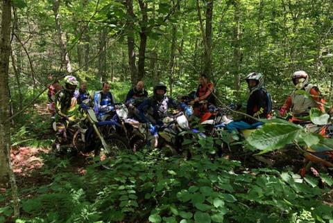 Several dirt bikers stopped in the woods for a photo