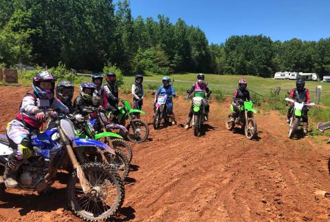 Women dirt bike riders chat in a group